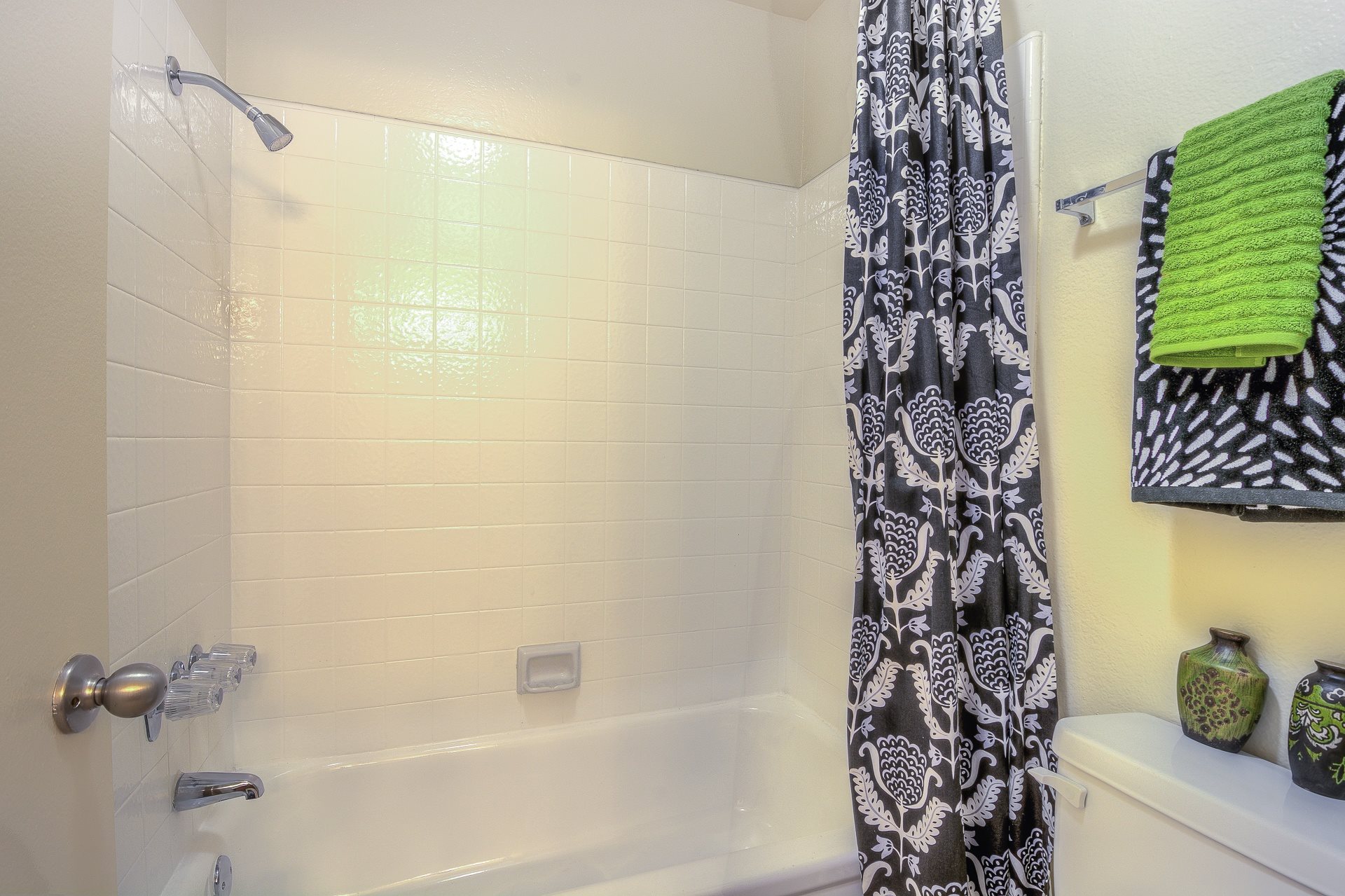 A bathroom with a shower curtain and a green towel.,A bathroom with a shower curtain and a green towel.
